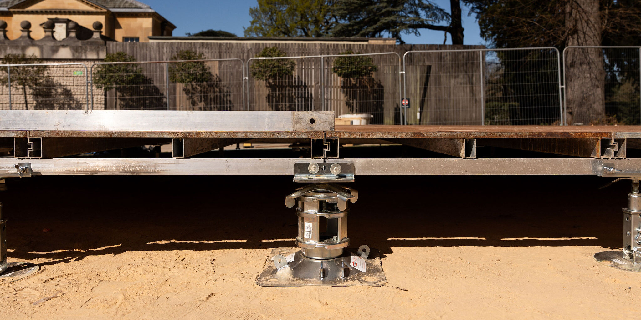 Close-up of FloorStak telescopic support columns and intermediate i-Stak units levelling a marquee floor on uneven ground.
